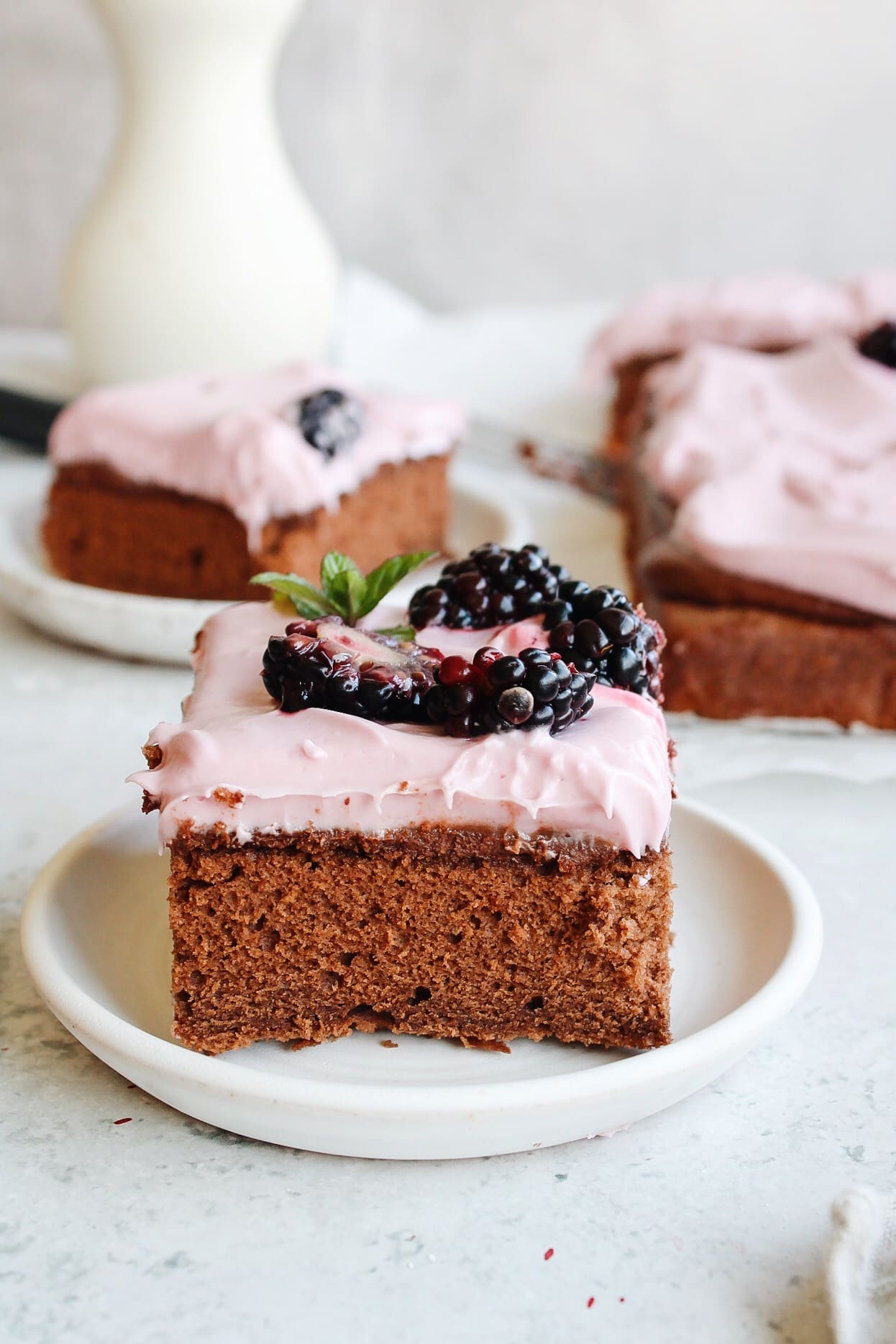 slice of blackberry chocolate cake with blackberry cream cheese frosting on a white plate