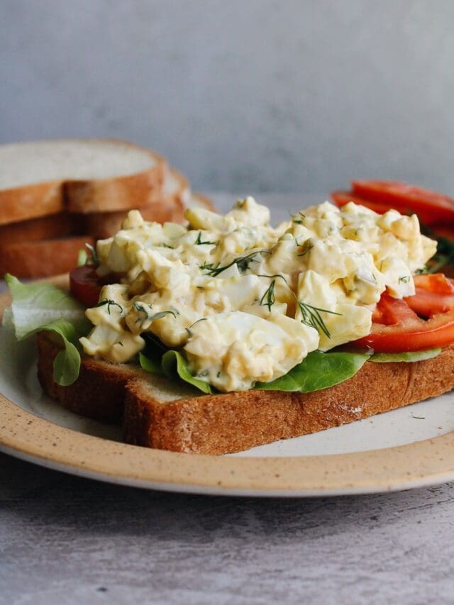 egg salad with pickles on bread with lettuce and tomato