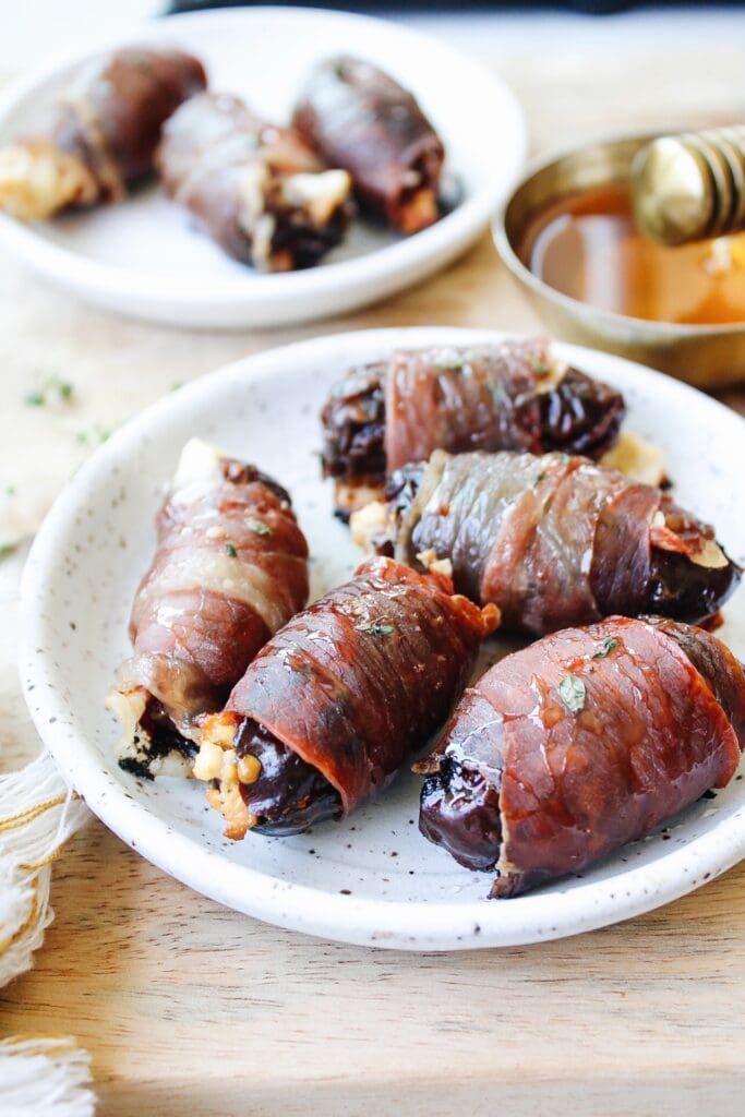 goat cheese stuffed prosciutto wrapped dates on a small plate