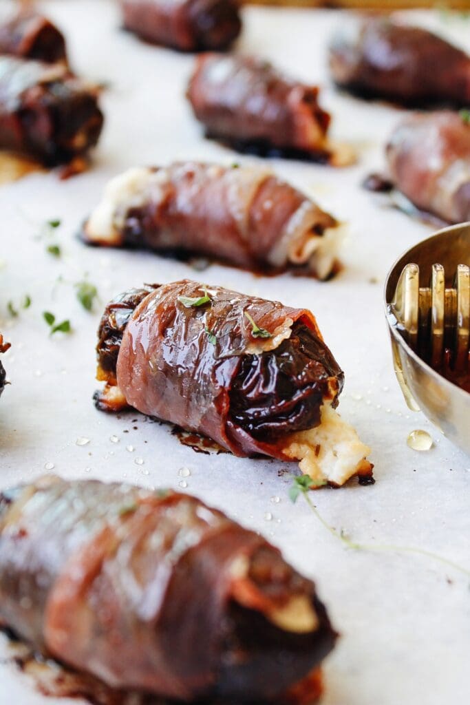 side view of prosciutto wrapped date with goat cheese oozing out.