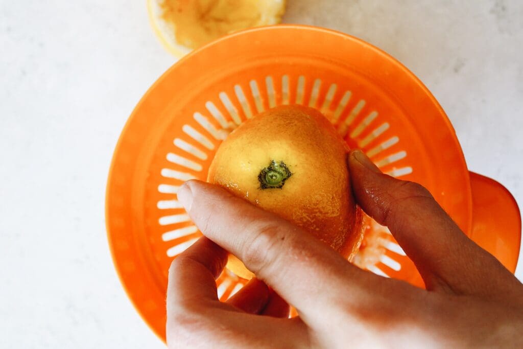 a hand juicing a lemon using a citrus juicer