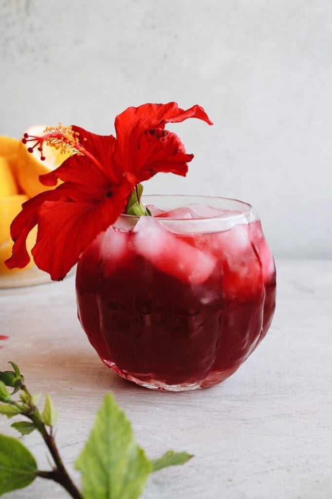 hibiscus lemonade in a clear glass with a hibiscus flower