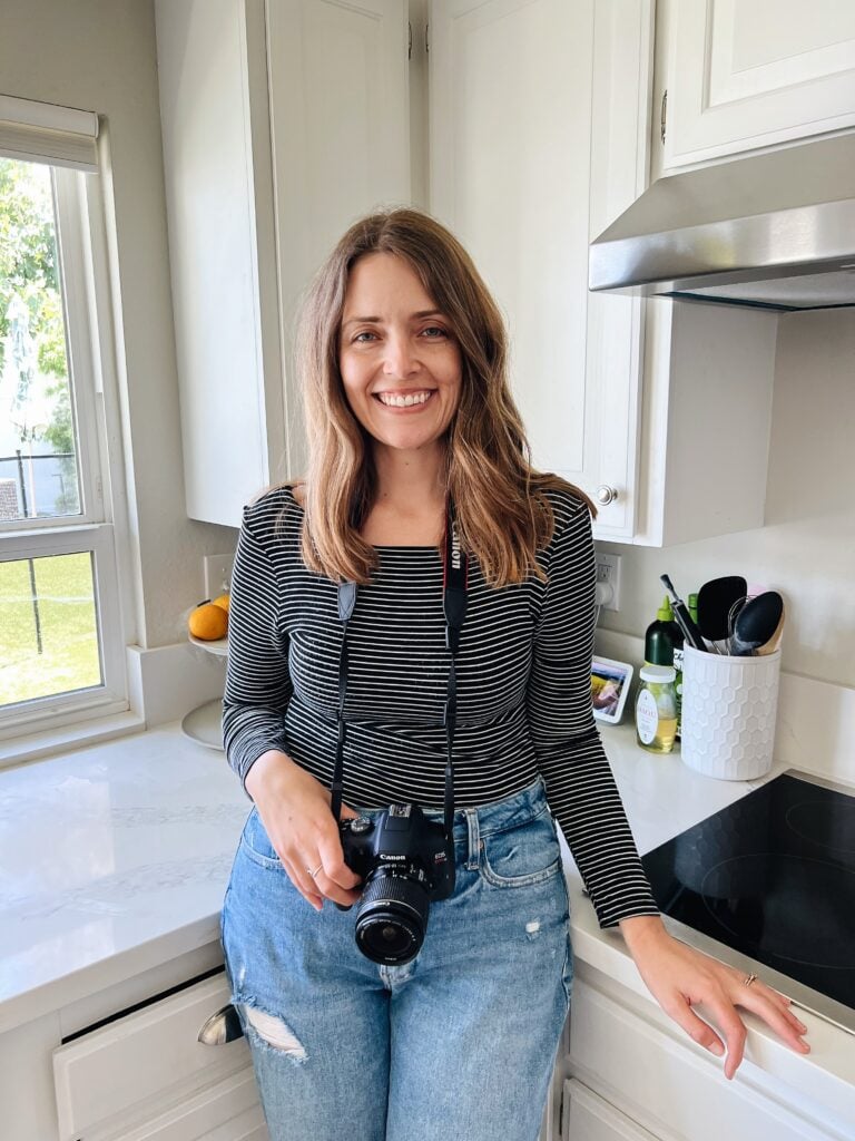 becky standing in kitchen with camera