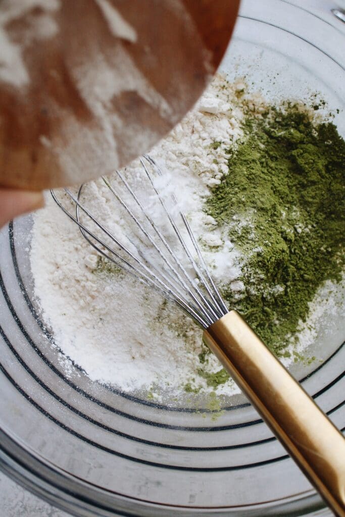 dry ingredients for matcha pancakes being whisked in a large mixing bowl