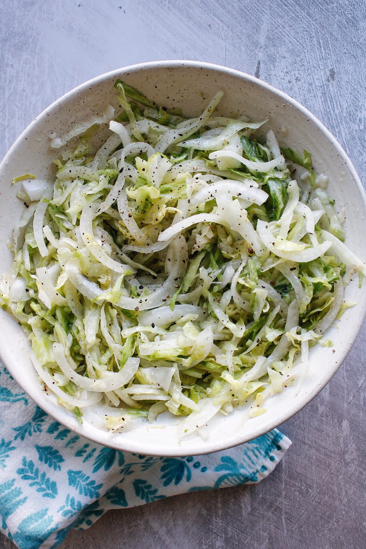 pickled lettuce in a white bowl with a blue napkin next to it