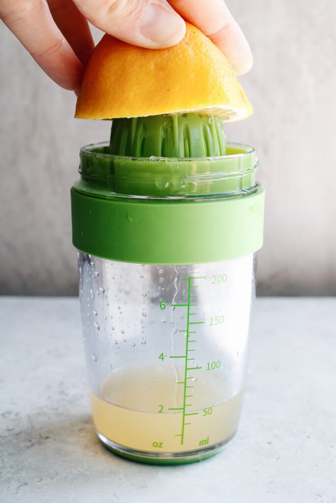 a salad dressing shaker container with a juicer on top
