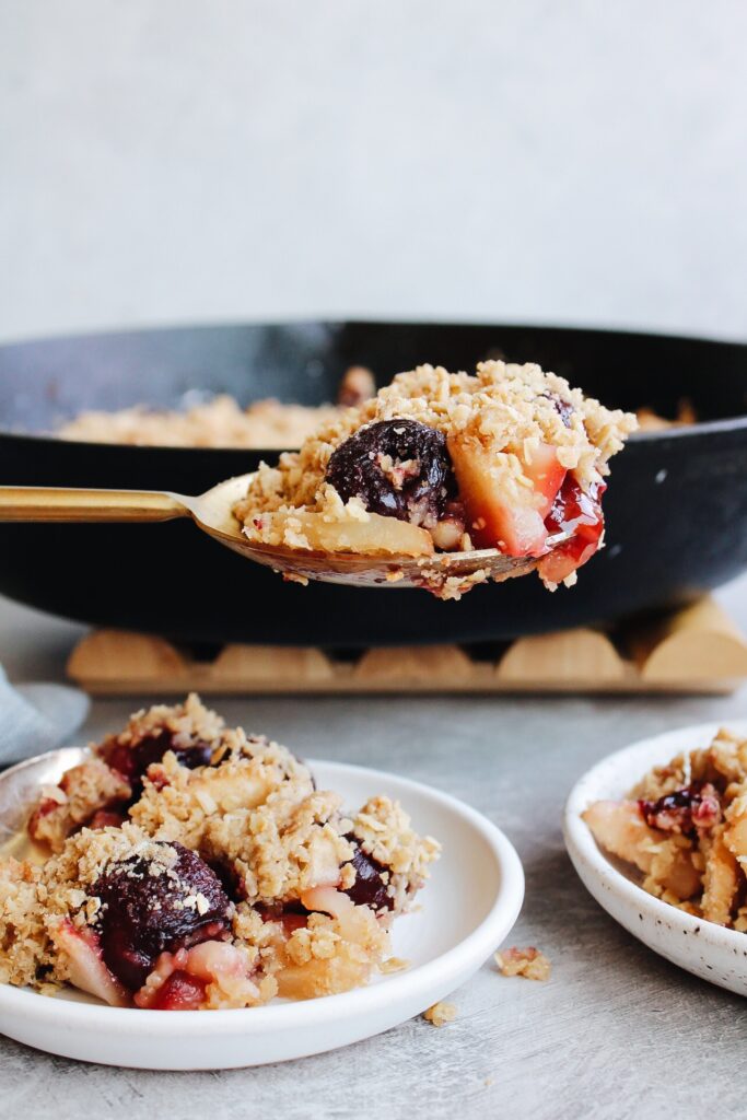 cherry apple crumble on a large serving spoon over two white plates