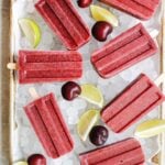 cherry popsicles on a tray with ice, limes and lime wedges