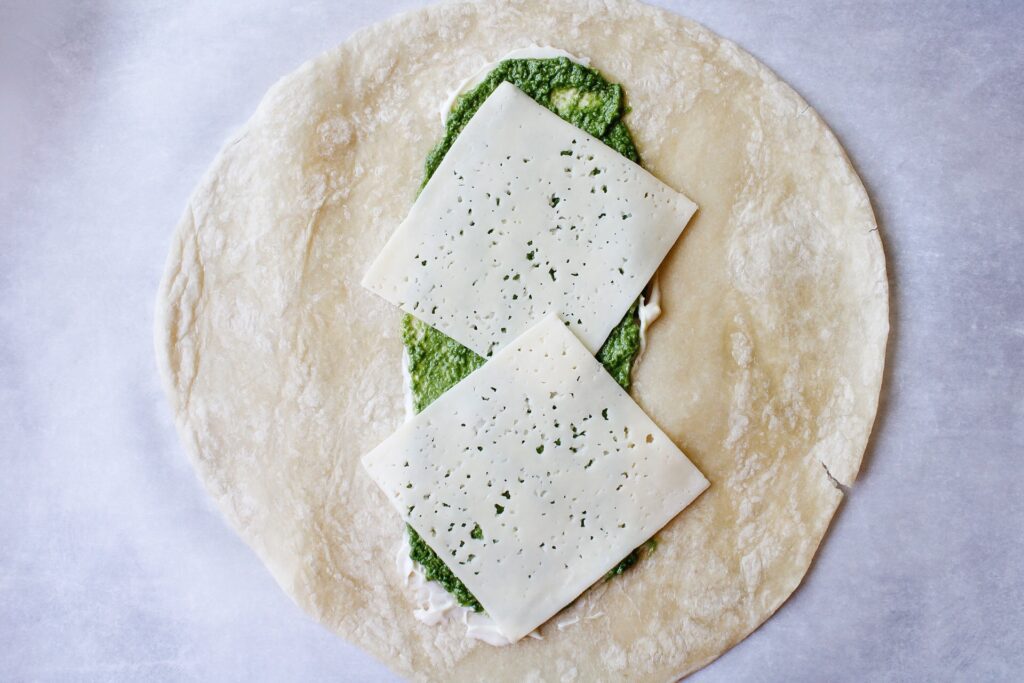 cheese on tortilla with pesto and mayo for turkey pesto wraps