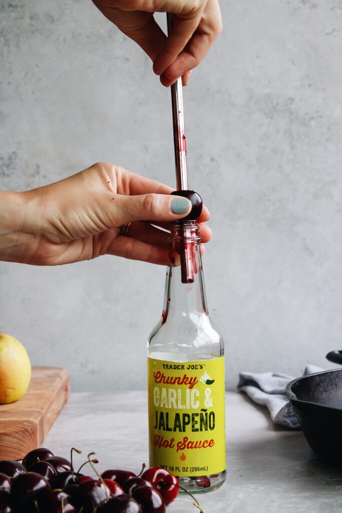 metal straw going through a cherry to remove pit