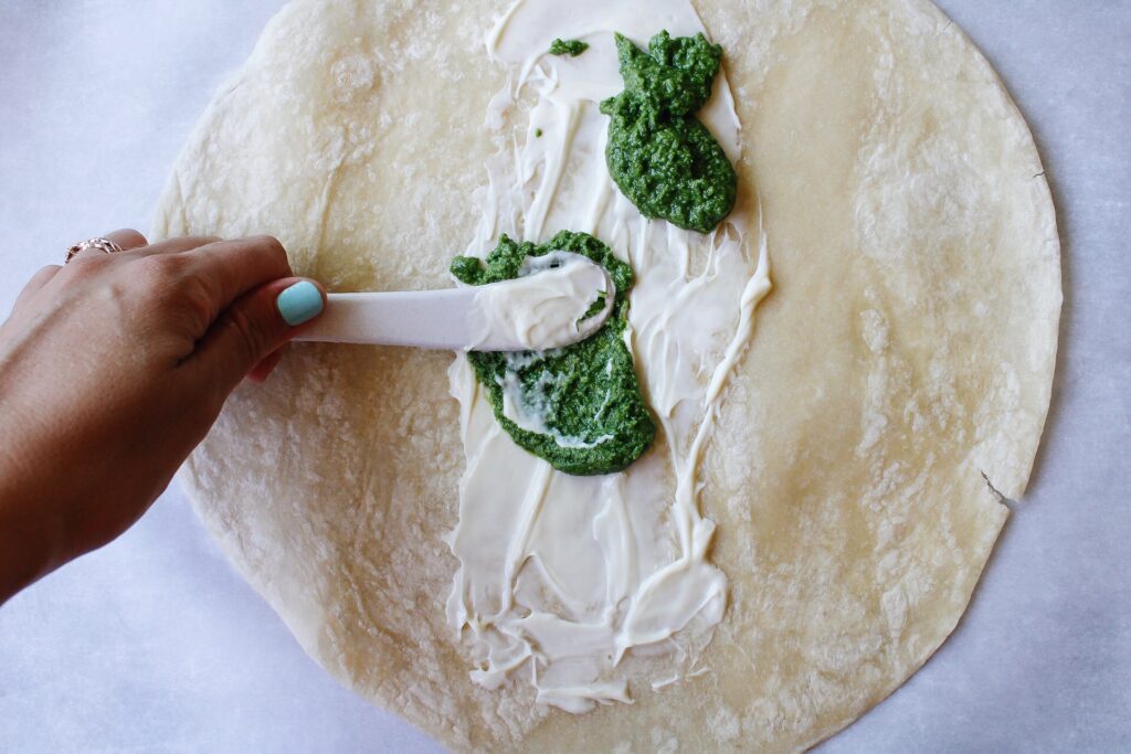 pesto spread on a tortilla with mayo