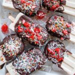 vegan banana split popsicles on a cookie sheet lined with ice