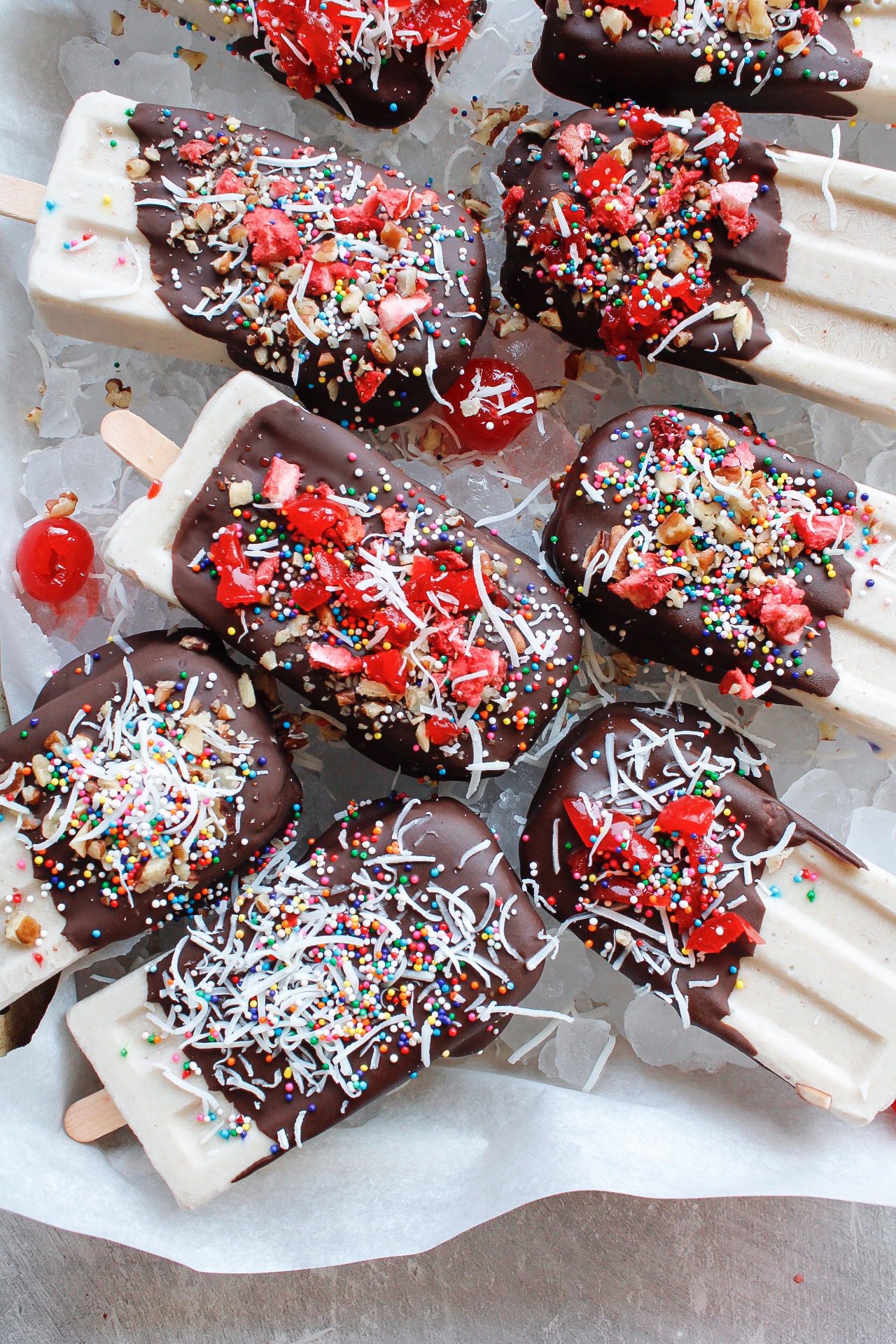 vegan banana split popsicles on a cookie sheet lined with ice