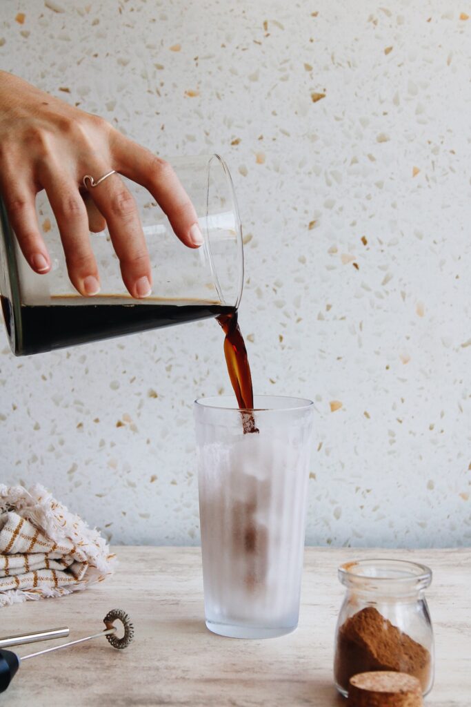 coffee being poured in a glass with ice