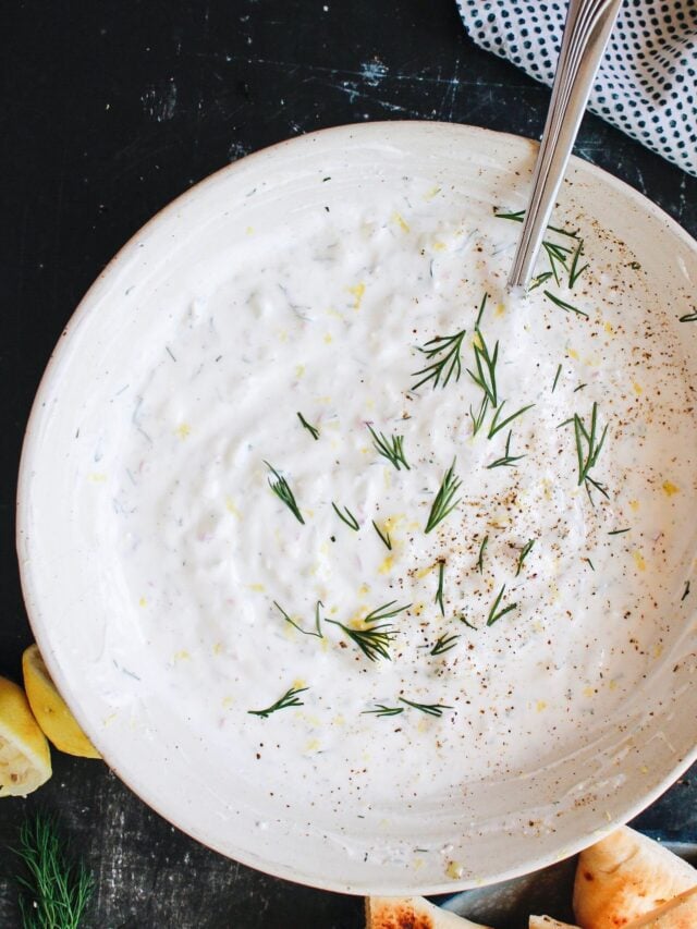 feta tzatziki in a white bowl topped with fresh dill