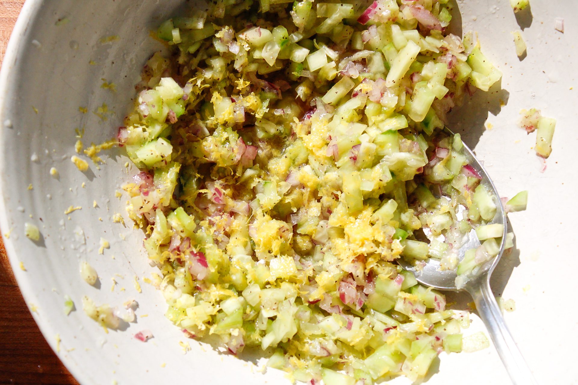 mixing cucumber and onion in a bowl for tzatziki sauce