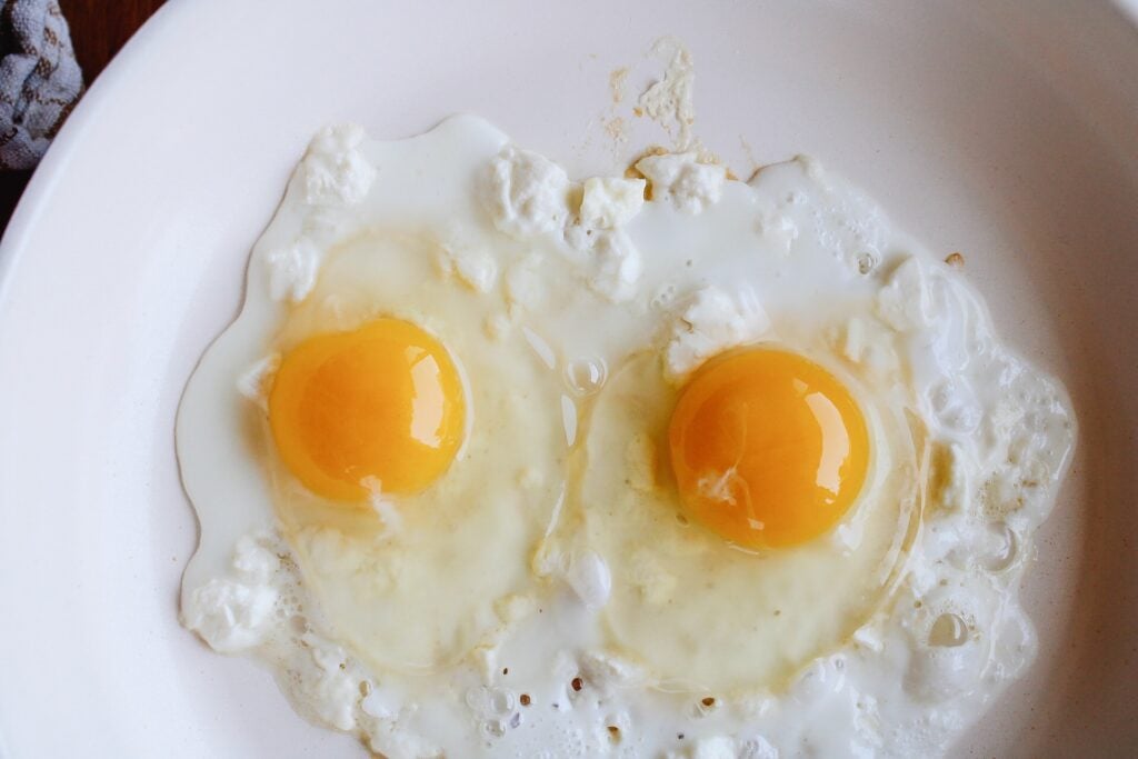 eggs cracked into pan on top of feta cheese