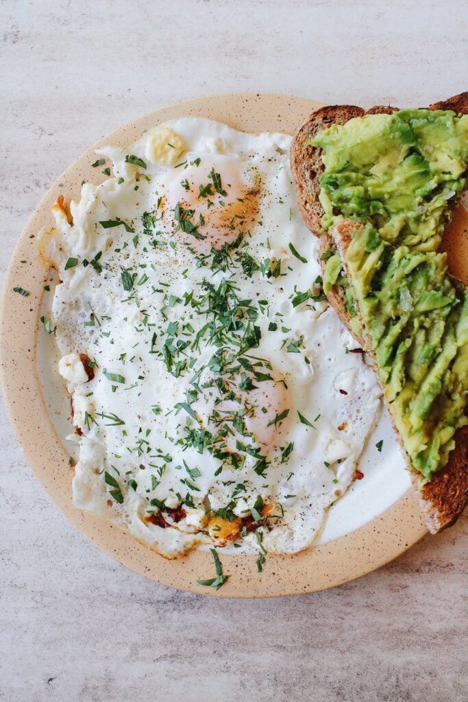 feta fried eggs on a plate with avocado toast