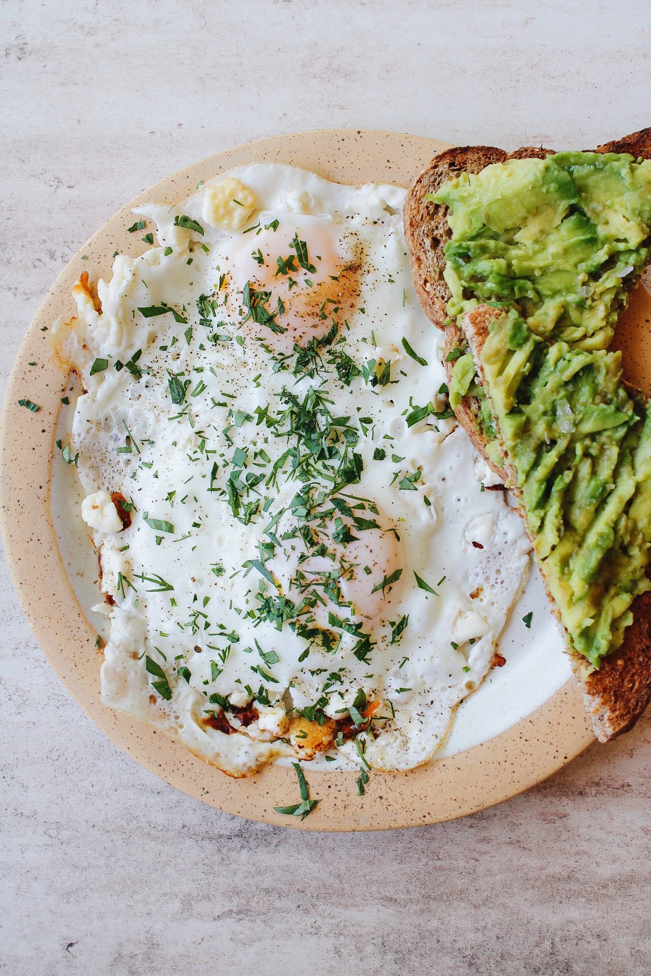 feta fried eggs on a plate with a piece of avocado toast