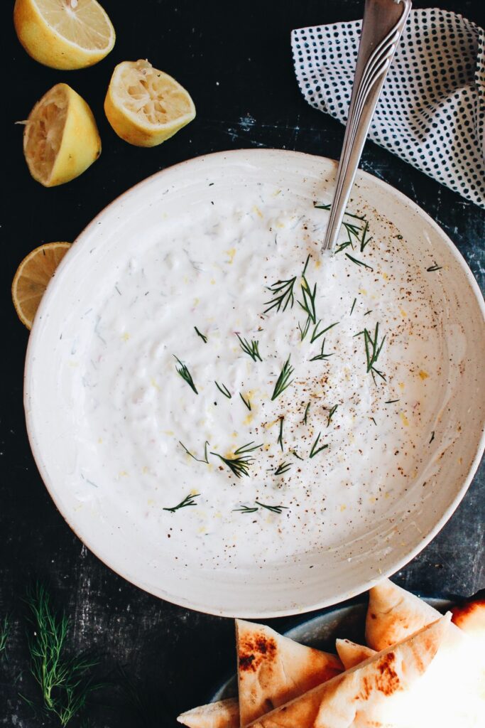 feta tzatziki sauce in a white bowl with pita bread beside it