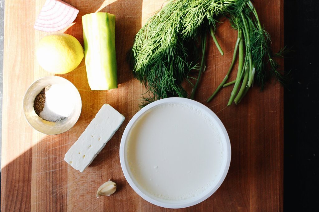 ingredients for feta tzatziki sauce on a wood cutting board