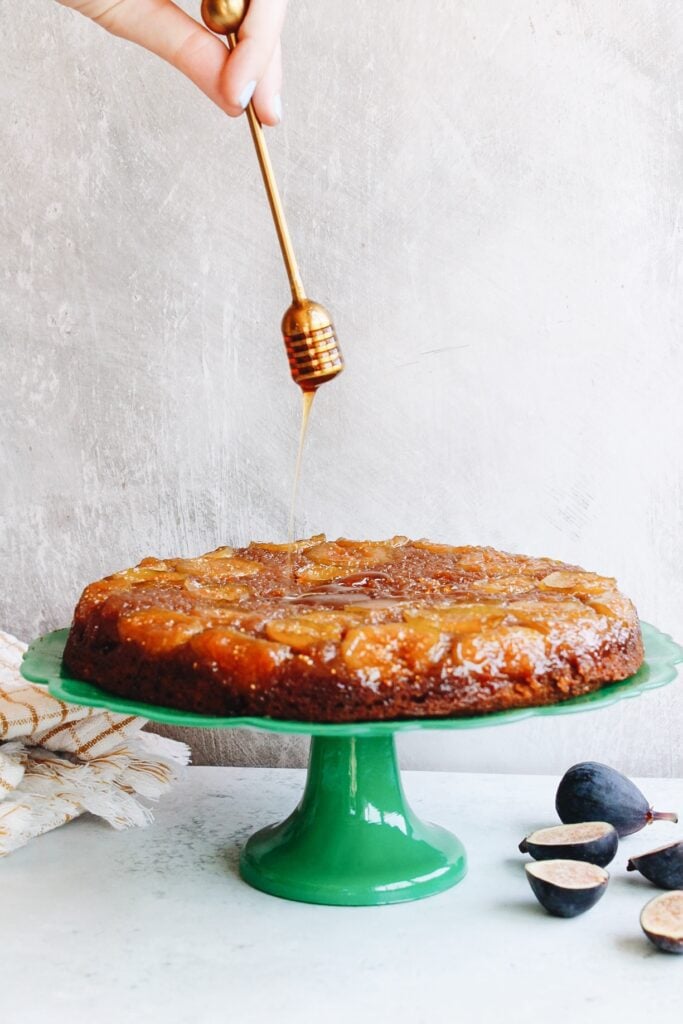 honey dipper drizzling honey over fig honey cake