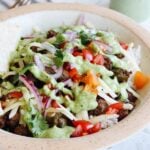 ground beef taco bowls with cream cilantro sauce in a bowl