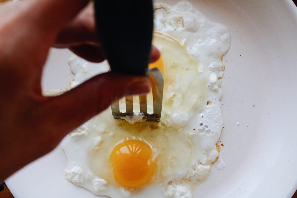 spatula scooting egg whites aside to cook