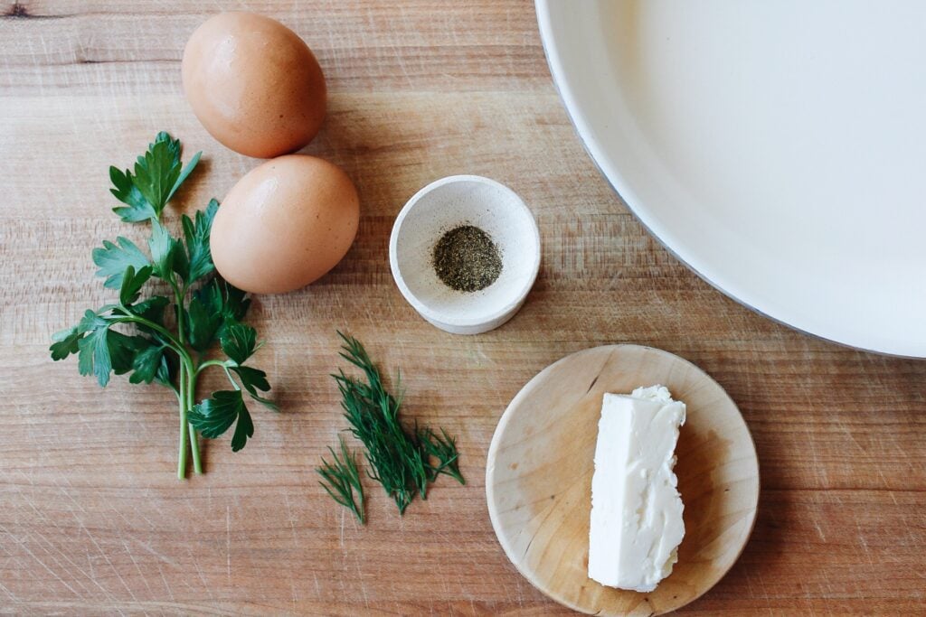 ingredients for feta fried eggs on a wooden cutting board