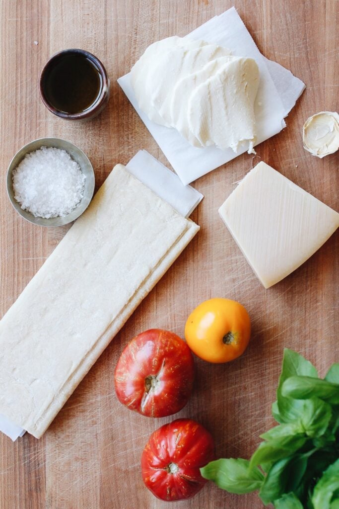 ingredients for puff pastry tomato tart on a wooden cutting board