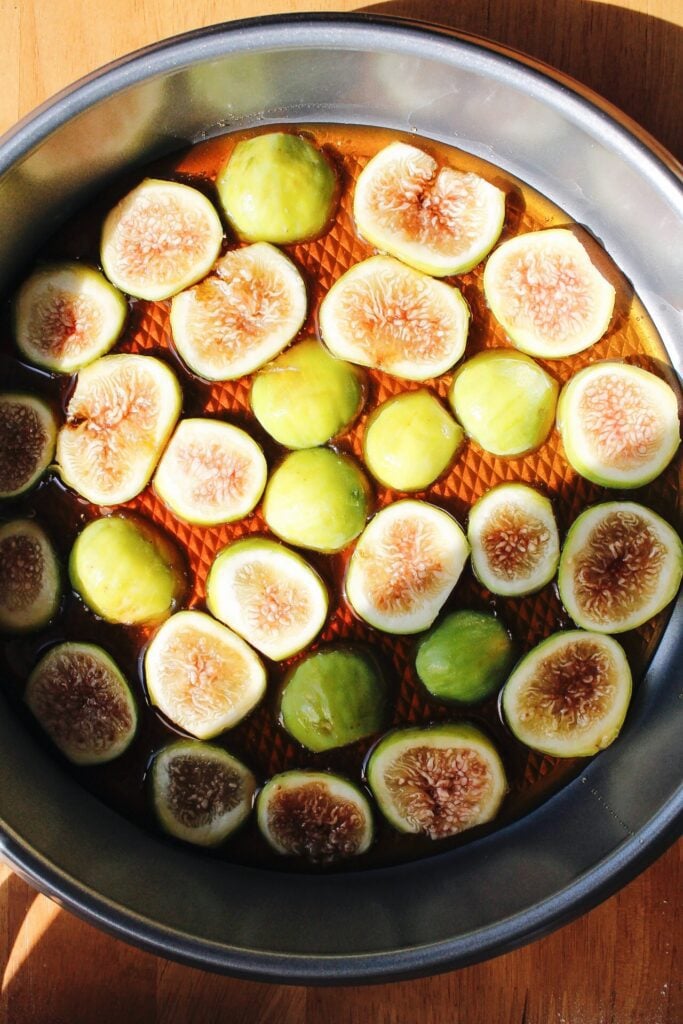 sliced figs in honey in the bottom of a cake pan