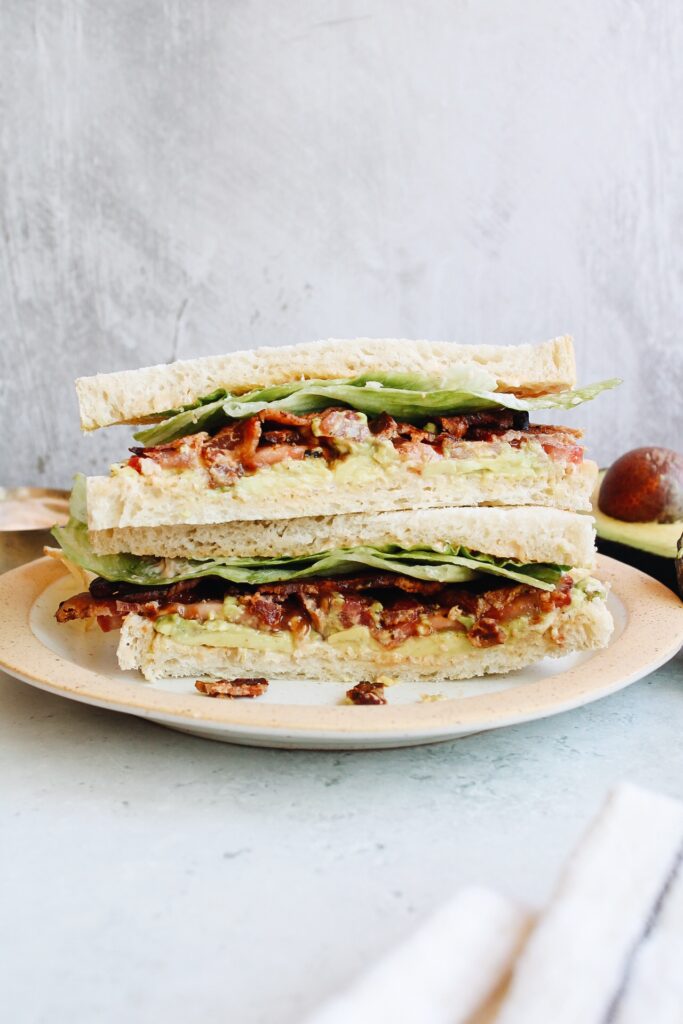 Avocado BLT sandwich stacked on a plate 