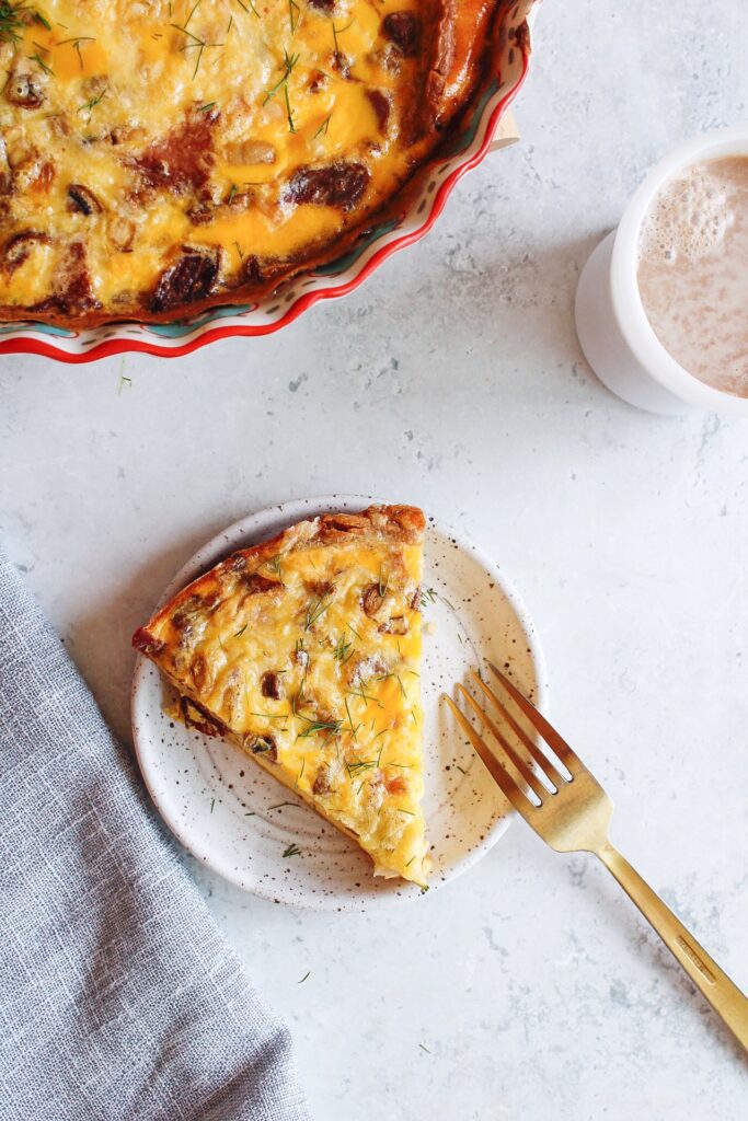 bacon mushroom quiche on a white plate with a coffee