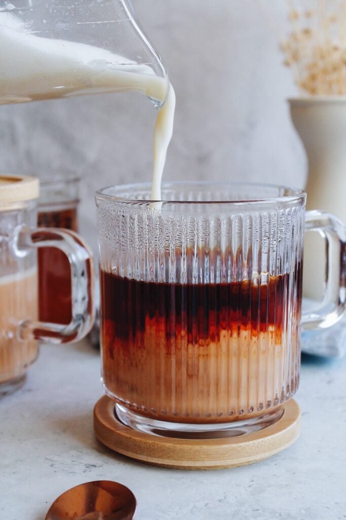 frothed + warmed milk being poured over steeped rooibos tea