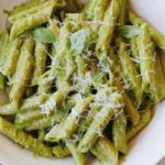 pesto without garlic on penne pasta in a white bowl