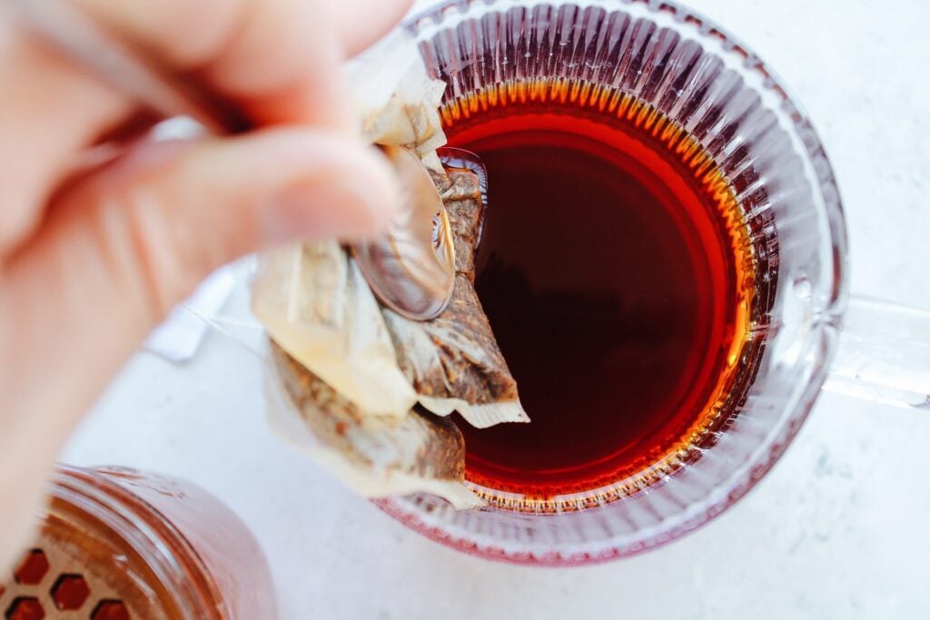 rooibos tea bags being removed from mug after steeping