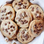 carob cookies stacked in a basket lined with parchment paper