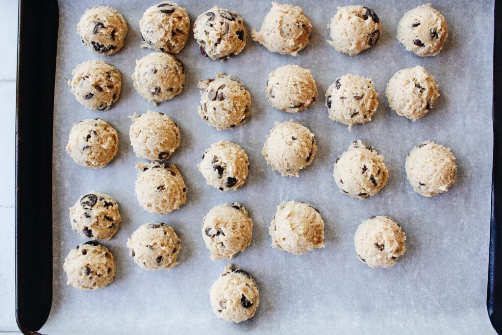 scooped cookie dough on a baking sheet lined with parchment ready to be frozen