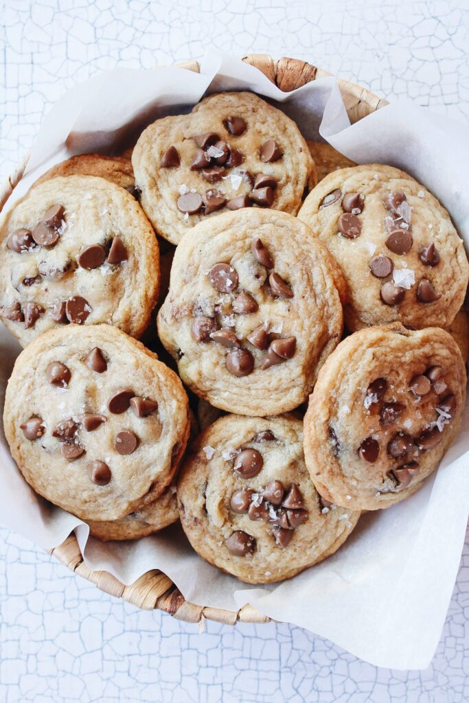 carob cookies stacked in a basket lined with parchment paper 