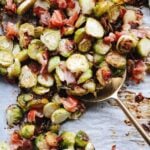 roasted Brussel sprouts with prosciutto on a baking sheet with a large golden serving spoon