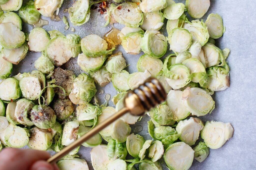 honey being drizzled on brussel sprouts