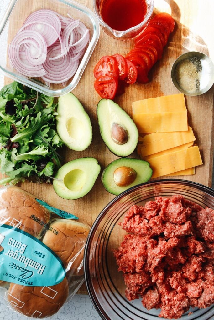 Ingredients for California burgers on a wooden cutting board 