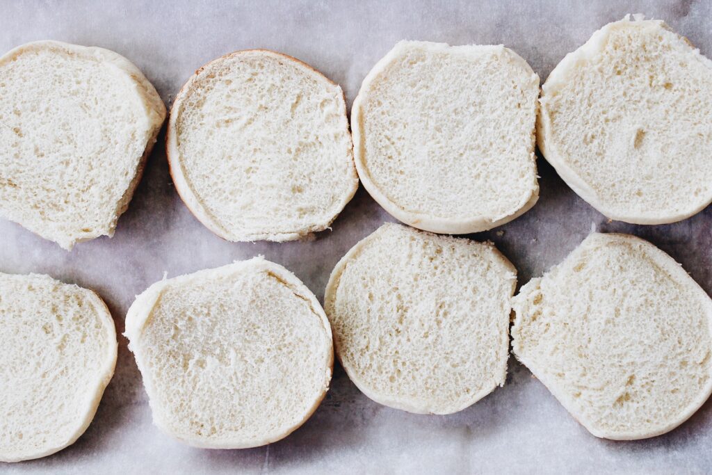 Burger buns on a baking sheet lined with parchment paper