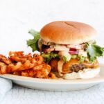 California burger with fries on a plate with a blue napkin next to it