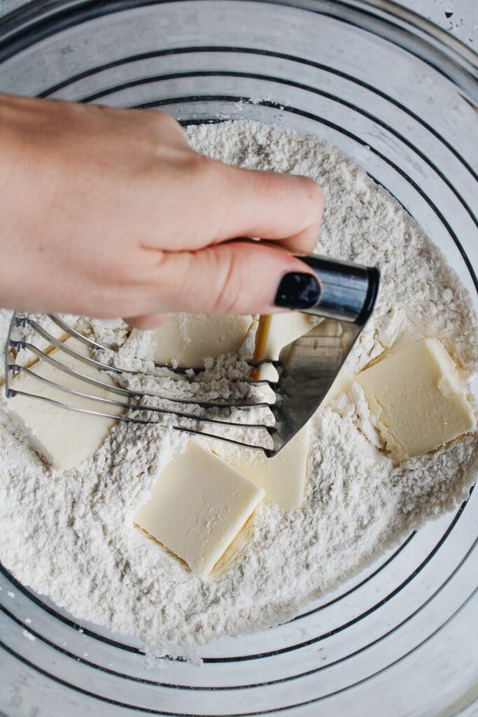 butter being cut into dry ingredients with a pastry blender