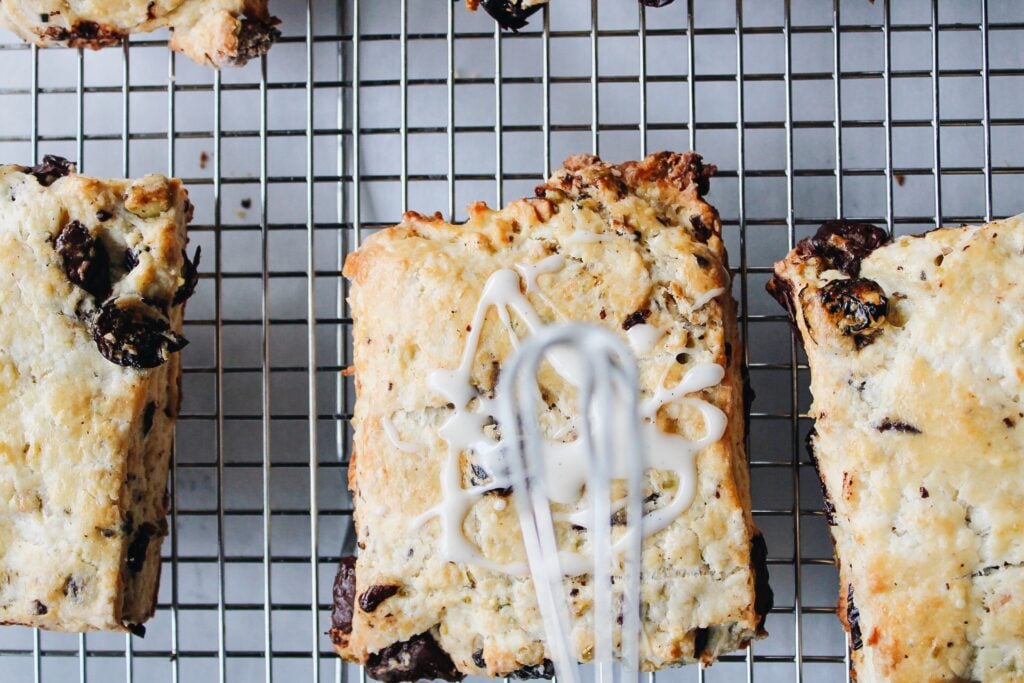 mini whisk drizzling icing onto a scone