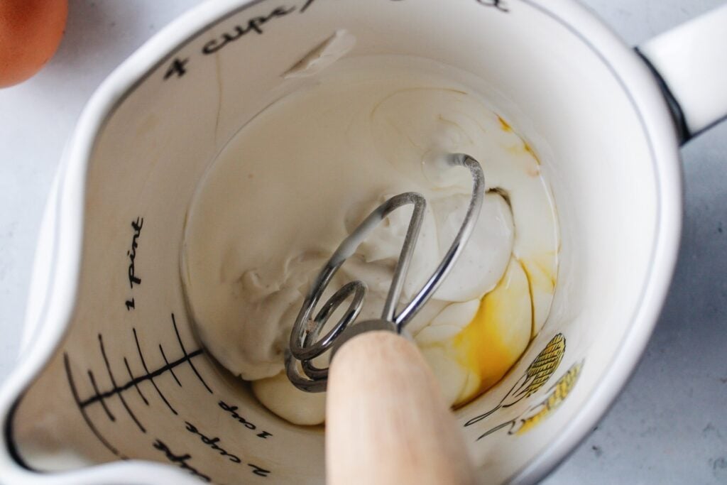 milk and egg being whisked in a large measuring cup