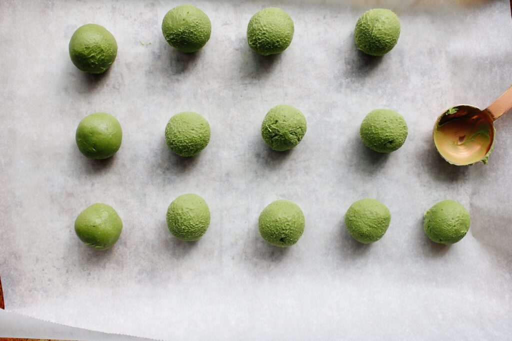 matcha truffle balls on a baking sheet lined with parchment