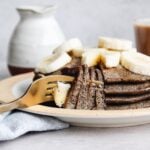 buckwheat banana pancakes stacked on a plate topped with bananas