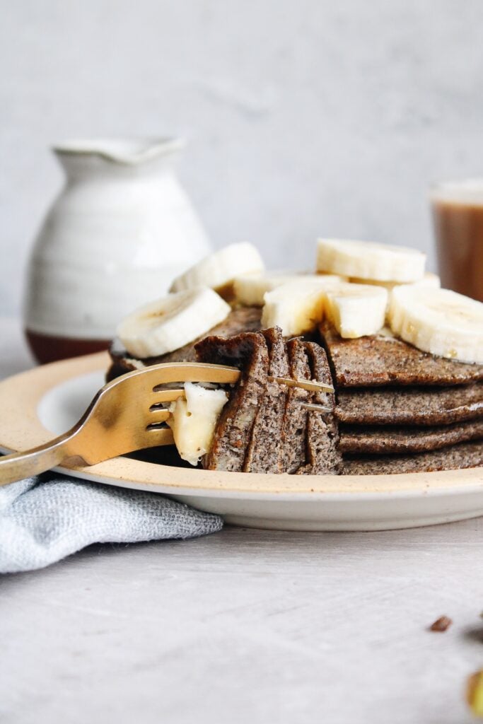 buckwheat banana pancakes stacked on a plate topped with bananas